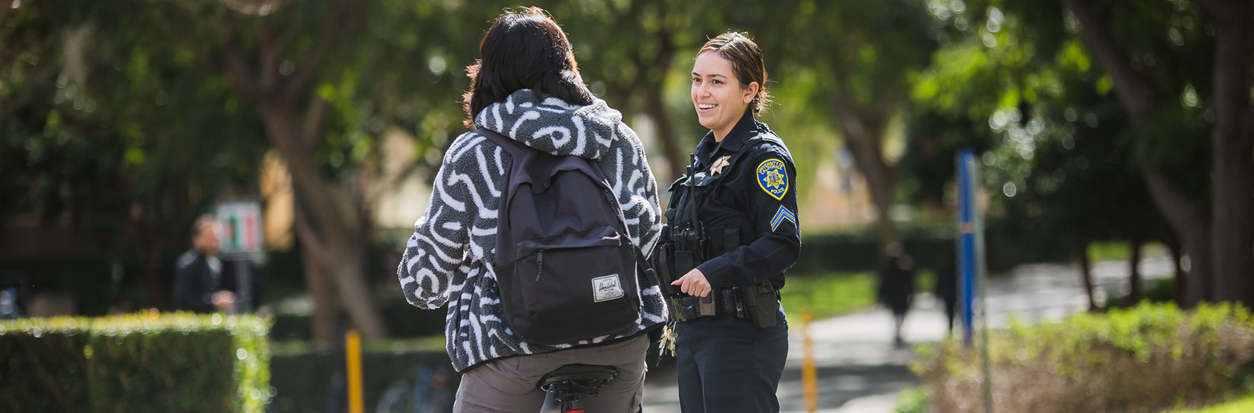 Officer smiling and speaking to student on UCI Ring Road