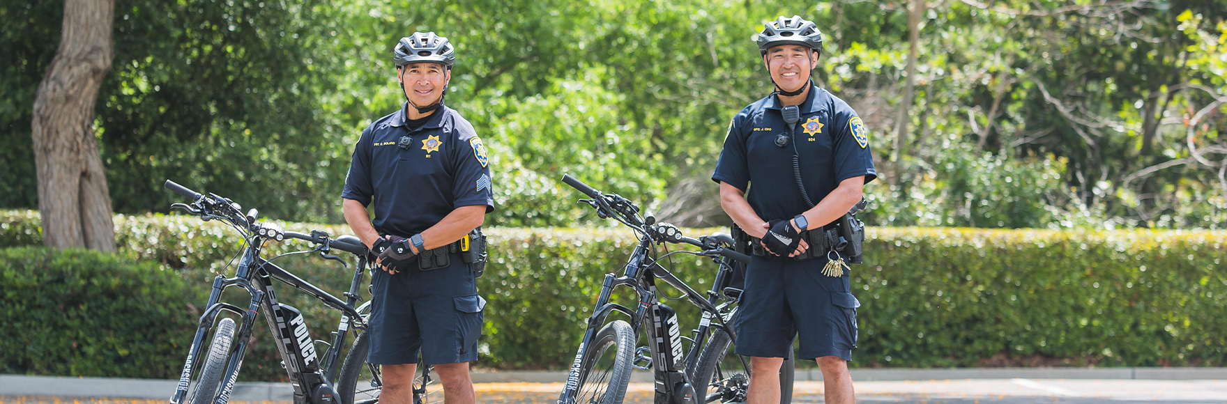 Sgt. Bolano and Ofc. Cho smiling next to their police bicycles