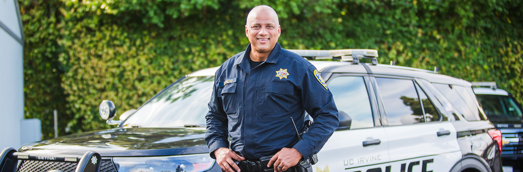 Officer Iraldo smiling in front of a police car